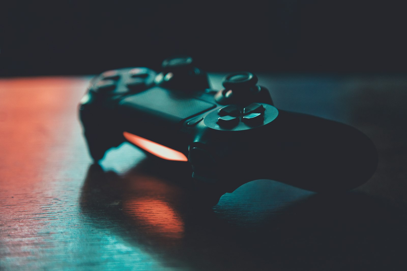 A PlayStation console controller lit with neon reflections
